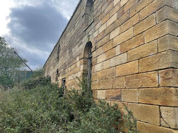 A stone wall with a window
Description automatically generated